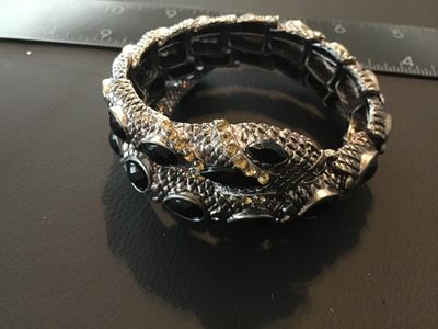 Sale Photo Thumbnail #119: Textured silver-tone snake wrap bracelet featuring black tear-shaped cabochon stones and small yellow crystal accents around the snake head. Stretch band design with coiled body effect. Good pre-owned condition with minor surface wear. Measures approximat