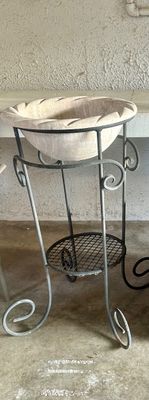 Sale Photo Thumbnail #36: Concrete or stone basin with a scalloped rim resting on a wrought iron plant stand featuring scrollwork details and a lower mesh shelf.