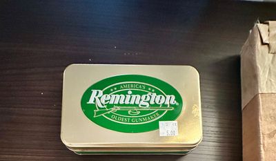 Sale Photo Thumbnail #5: Vintage Remington gold-tone collectible metal storage tin featuring green branded logo on the lid.