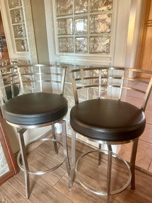 Sale Photo Thumbnail #32: Pair of modern brushed metal swivel bar stools with round black vinyl seats and curved ladder backs.