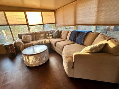 Sale Photo Thumbnail #18: Large contemporary sectional sofa in beige fabric paired with an oval upholstered ottoman with a wood top and geometric pattern base.