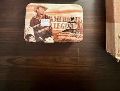 Sale Photo Thumbnail #26: John Wayne "American Legend" collectible metal storage tin featuring cowboy artwork and signature graphic.