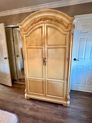 Sale Photo Thumbnail #13: French Provincial style arched wooden armoire with carved scrollwork top detail and two paneled doors.