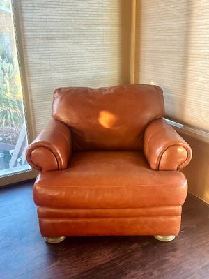 Sale Photo Thumbnail #21: Cognac-colored leather armchair with rolled arms, plush cushioning, and short round legs.