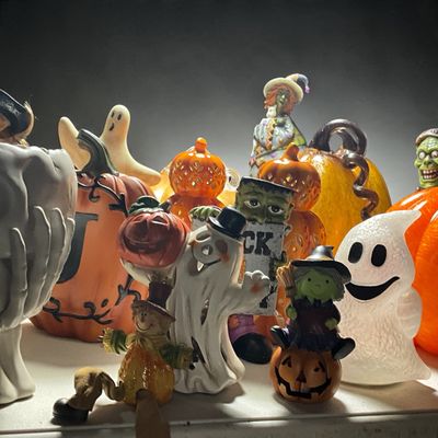 Sale Photo Thumbnail #20: Collection of festive Halloween decorations including ceramic and glass pumpkins, ghost figurines, a Frankenstein statue, and various witch tabletop accents.