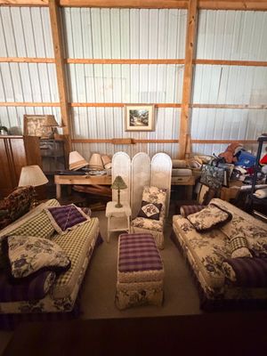 Sale Photo Thumbnail #68: Matching floral and purple plaid upholstered living room set, including two sofas, a accent chair, and an ottoman, set in a barn-style storage area.