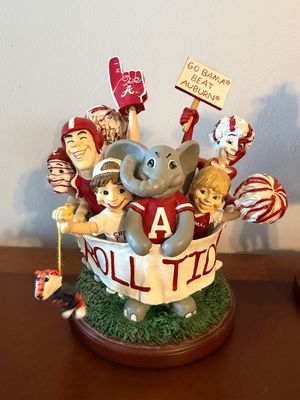 Sale Photo Thumbnail #48: University of Alabama Crimson Tide football fans and mascot resin figurine featuring Big Al holding a 'Roll Tide' banner, mounted on a round wooden base.
