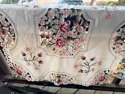 Sale Photo Thumbnail #51: Off-white embroidered tablecloth featuring cutwork and pink and red floral designs, shown draped outdoors.