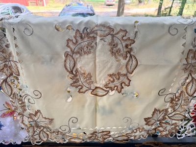 Sale Photo Thumbnail #50: Off-white square tablecloth featuring brown embroidered autumn leaves and cutwork detailing throughout.