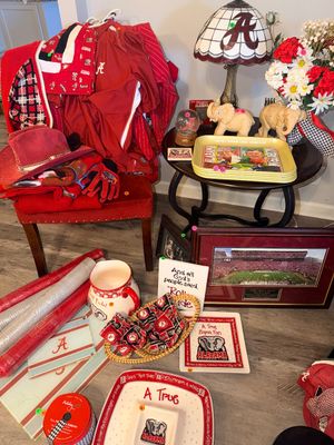 Sale Photo Thumbnail #6: Collection of University of Alabama Crimson Tide memorabilia, featuring apparel, home decor, a stained-glass style lamp, elephant figurines, and framed stadium art.