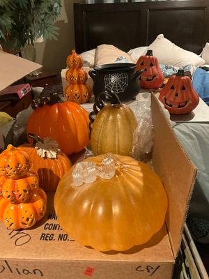 Sale Photo Thumbnail #22: Collection of autumn and Halloween decorations, featuring blown glass, ceramic, and resin pumpkins alongside a black cauldron with spiderweb detail.