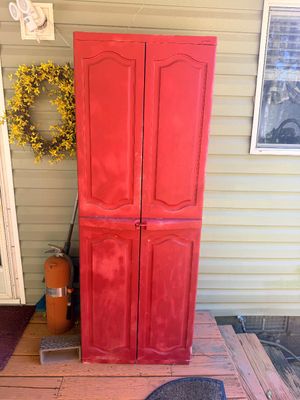 Sale Photo Thumbnail #11: Tall, red painted resin or plastic storage cabinet with raised panel doors, shown outdoors on a deck.