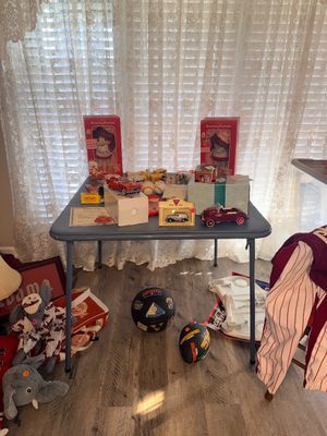 Sale Photo Thumbnail #5: Folding table displaying vintage collectibles including boxed Strawberry Shortcake dolls, die-cast toy cars, and sports memorabilia.