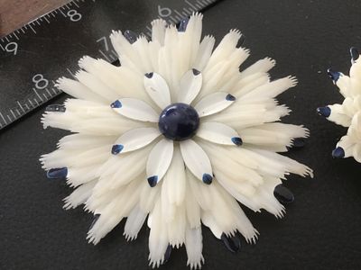 Sale Photo Thumbnail #135: Matching 3-piece vintage jewelry set featuring a large floral brooch pin and two clip-on earrings. Crafted from layered white celluloid petals with painted blue tips and a dark blue center cabochon accent. Brooch measures approximately 3.5 inches across. 