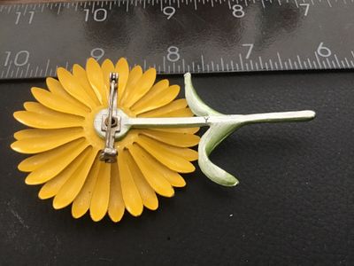 Sale Photo Thumbnail #91: A mid-century style vintage enamel brooch in the shape of a yellow flower with a brown center dome and green stem/leaves. Made of painted/enameled metal. Pin back attachment is intact. Measures approximately 3 inches across. Shows minor finish wear and li