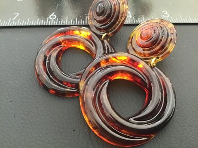 Sale Photo Thumbnail #43: Pair of statement clip-on drop earrings featuring a translucent faux tortoiseshell amber lucite/acrylic design with swirl pattern hoops and layered top buttons. Gold-tone clip backs with comfort pads. Total length is approximately 3 inches. Good vintage c