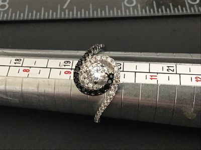 Sale Photo Thumbnail #182: silver bypass swirl ring featuring a central clear round cubic zirconia or crystal, surrounded by swirling bands of pave-set clear and black stones. Marked 925 on the inner band. Measures approximately size 9.5 on a ring mandrel. Good condition with light
