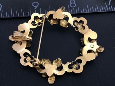 Sale Photo Thumbnail #161: Vintage gold-tone openwork wreath brooch featuring embossed flowers accented with round turquoise-colored cabochons. Includes a rollover C-clasp pin back and an integrated pendant bail on the reverse for dual wear as a brooch or pendant. Measures approxim