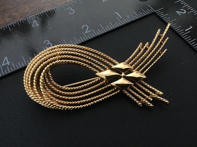 Sale Photo Thumbnail #14: Vintage Monet gold-tone brooch featuring textured, twisted rope strands in a modern abstract loop design with polished diamond-shaped central accents. Signed 'MONET ©' on the back. Measures approximately 2.75 inches long. Features a standard rollover saf