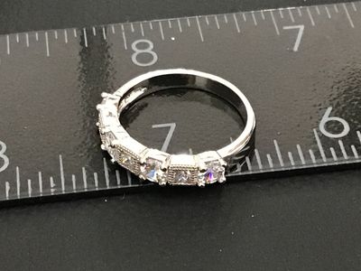 Sale Photo Thumbnail #235: Silver-tone band ring set with five clear cubic zirconia or crystal stones featuring alternating round and square shapes with milgrain border details. Measures approximately size 8 on a ring mandrel. Good condition with minimal wear.