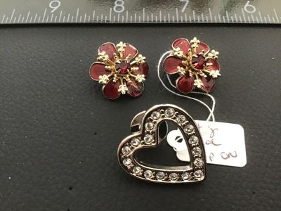 Sale Photo Thumbnail #48: A 3-piece lot of vintage costume jewelry featuring a pair of gold-tone flower clip-on earrings with deep red enamel petals and central faux ruby red rhinestones, alongside a silver-tone open heart lapel pin lined with clear rhinestones and secured with a 