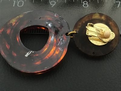 Sale Photo Thumbnail #44: Pair of statement clip-on drop earrings featuring a translucent faux tortoiseshell amber lucite/acrylic design with swirl pattern hoops and layered top buttons. Gold-tone clip backs with comfort pads. Total length is approximately 3 inches. Good vintage c