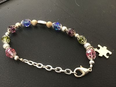 Sale Photo Thumbnail #130: A beaded charm bracelet featuring colorful faceted crystal beads with decorative filigree caps, silver spacer beads, and a sterling silver puzzle piece charm stamped '925'. Includes an adjustable chain extender with a lobster clasp closure. In good pre-ow