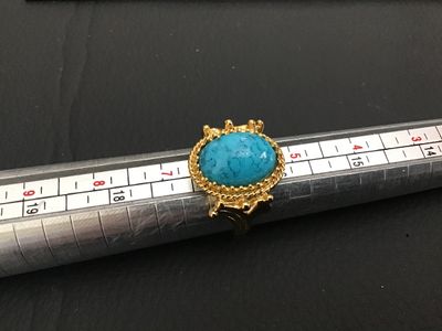 Sale Photo Thumbnail #257: Vintage gold tone statement ring featuring a large oval faux turquoise cabochon with a twisted rope textured border and ornate setting. Measures approximately size 6 on ring mandrel. Good vintage condition with light finish wear visible on the band.