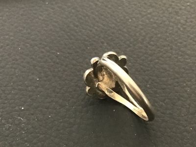 Sale Photo Thumbnail #77: Vintage Southwestern style silver ring featuring a central red stone cabochon set in a saw-tooth bezel with scalloped and bead accents. Shown on a ring mandrel as approximately size 7. Features a split-shank band design. Shows minor surface wear and natur