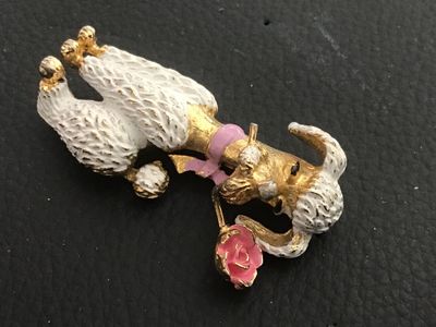 Sale Photo Thumbnail #16: Vintage gold-tone textured metal brooch featuring a French poodle figure with white textured enamel fur, a pink ribbon bow collar, and holding a pink enamel rose in its mouth. Measures approximately 2 inches long. Features a standard pin back clasp. Shows