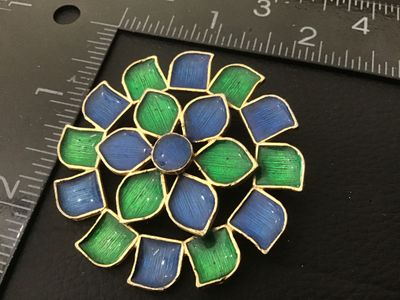 Sale Photo Thumbnail #69: A vintage gold-tone floral brooch featuring vibrant blue and green enamel accents. Marked 'FLORENZA ©' on the back with a secure roll-over safety clasp. Measures approximately 1.75 inches in diameter. In good vintage condition with minor surface wear con