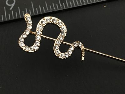 Sale Photo Thumbnail #213: Gold-tone metal stick pin featuring a serpentine snake design encrusted with clear pave rhinestones. Measures approximately 3 inches in total length. Good condition with all stones intact.
