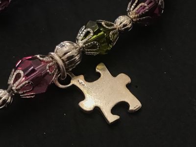 Sale Photo Thumbnail #129: A beaded charm bracelet featuring colorful faceted crystal beads with decorative filigree caps, silver spacer beads, and a sterling silver puzzle piece charm stamped '925'. Includes an adjustable chain extender with a lobster clasp closure. In good pre-ow