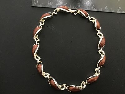 Sale Photo Thumbnail #26: Vintage gold-tone link necklace featuring paisley/tear-drop shaped links inset with smooth brown enamel or lucite cabochons and textured leaf trim detailing. Features a fold-over clasp mechanism. Measures approximately 15 to 16 inches in total length. Goo