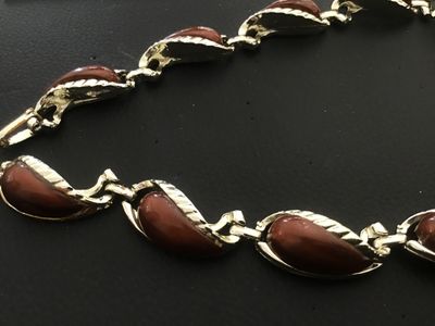 Sale Photo Thumbnail #28: Vintage gold-tone link necklace featuring paisley/tear-drop shaped links inset with smooth brown enamel or lucite cabochons and textured leaf trim detailing. Features a fold-over clasp mechanism. Measures approximately 15 to 16 inches in total length. Goo
