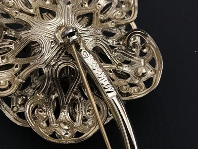 Sale Photo Thumbnail #154: Vintage gold-tone flower brooch by Sarah Coventry featuring ornate filigree work accenting pink/fuchsia aurora borealis rhinestones. Signed "© SARAH COV" on the back stem. Features a secure pin back clasp. Measures approximately 3 inches long. In good vi