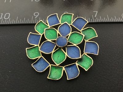 Sale Photo Thumbnail #68: A vintage gold-tone floral brooch featuring vibrant blue and green enamel accents. Marked 'FLORENZA ©' on the back with a secure roll-over safety clasp. Measures approximately 1.75 inches in diameter. In good vintage condition with minor surface wear con