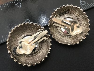 Sale Photo Thumbnail #122: Pair of vintage round silver-tone clip-on earrings featuring prominent faceted cobalt blue  center  set in a ribbed dome border. Textured textured backs with clip fastenings. Each earring measures approximately 1 inch in diameter. Show light age-appropria