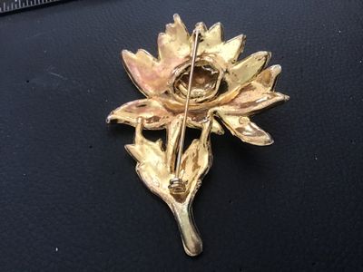 Sale Photo Thumbnail #112: Vintage gold-tone floral motif brooch pin featuring white enamel details and clear rhinestone accents. Shows noticeable surface wear, plating loss, enamel chipping, and age-related patina on the finish. The pin mechanism on the reverse is intact and funct