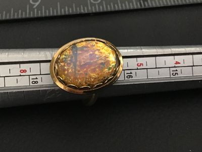 Sale Photo Thumbnail #260: Vintage Sarah Coventry costume ring featuring a large oval faux opal/dragon's breath glass cabochon in a crown-style gold-tone bezel setting. The band is adjustable and signed 'SARAH COV.' on the interior. Shows light age-appropriate wear and patina on me