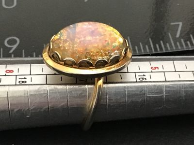 Sale Photo Thumbnail #262: Vintage Sarah Coventry costume ring featuring a large oval faux opal/dragon's breath glass cabochon in a crown-style gold-tone bezel setting. The band is adjustable and signed 'SARAH COV.' on the interior. Shows light age-appropriate wear and patina on me