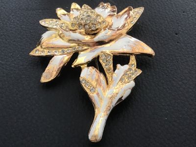Sale Photo Thumbnail #110: Vintage gold-tone floral motif brooch pin featuring white enamel details and clear rhinestone accents. Shows noticeable surface wear, plating loss, enamel chipping, and age-related patina on the finish. The pin mechanism on the reverse is intact and funct