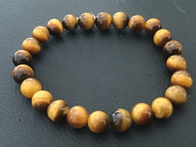 Sale Photo Thumbnail #128: Beaded stretch bracelet featuring polished natural tiger's eye round gemstones displaying characteristic chatoyancy in rich brown and golden tones. Good condition with smooth, polished beads.