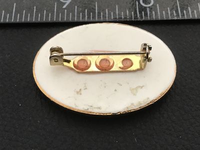 Sale Photo Thumbnail #51: Oval porcelain cabochon brooch featuring a classic vintage image of Santa Claus carrying a sack of toys. Framed in gold-tone metal with a pinback closure. Measures approximately 1.5 inches wide. Shows minor signs of age and wear on the back rim, pin mecha