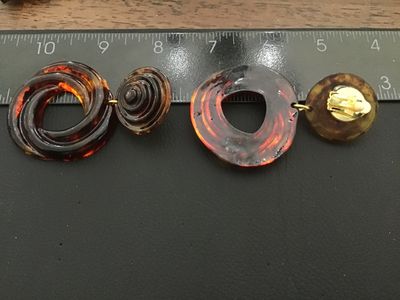 Sale Photo Thumbnail #46: Pair of statement clip-on drop earrings featuring a translucent faux tortoiseshell amber lucite/acrylic design with swirl pattern hoops and layered top buttons. Gold-tone clip backs with comfort pads. Total length is approximately 3 inches. Good vintage c