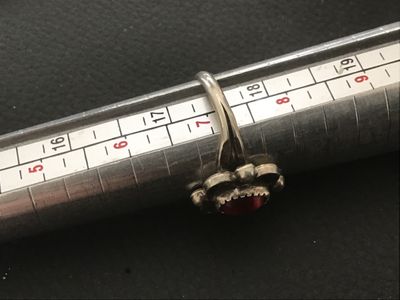 Sale Photo Thumbnail #76: Vintage Southwestern style silver ring featuring a central red stone cabochon set in a saw-tooth bezel with scalloped and bead accents. Shown on a ring mandrel as approximately size 7. Features a split-shank band design. Shows minor surface wear and natur
