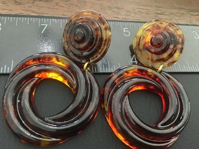 Sale Photo Thumbnail #45: Pair of statement clip-on drop earrings featuring a translucent faux tortoiseshell amber lucite/acrylic design with swirl pattern hoops and layered top buttons. Gold-tone clip backs with comfort pads. Total length is approximately 3 inches. Good vintage c