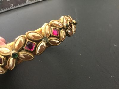 Sale Photo Thumbnail #131: Set of two statement bangle bracelets featuring yellow thread wrapping. One wider bangle is adorned with gold-tone leaf accents, pink/red and green rhinestones, and faux pearl details. The second thinner bangle features full rows of shimmering champagne/g