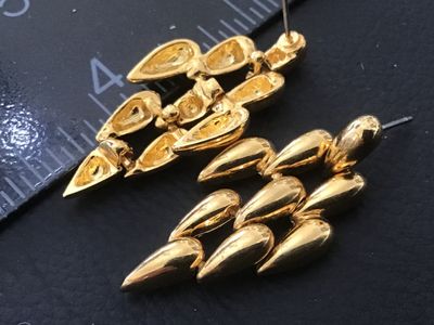 Sale Photo Thumbnail #74: Pair of vintage gold-tone fashion pierced earrings featuring articulated, multi-tiered teardrop shaped links. Includes bullet clutch plastic disc earring backs. Show light wear consistent with age and use. Measures approximately 1.5 inches long.