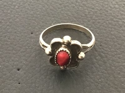 Sale Photo Thumbnail #78: Vintage Southwestern style silver ring featuring a central red stone cabochon set in a saw-tooth bezel with scalloped and bead accents. Shown on a ring mandrel as approximately size 7. Features a split-shank band design. Shows minor surface wear and natur